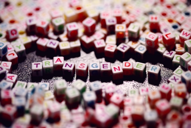 Beads with multicoloured letters on, spelling out the word transgender