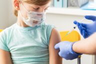 Little,Girl,In,Face,Mask,In,Doctor's,Office,Is,Vaccinated.